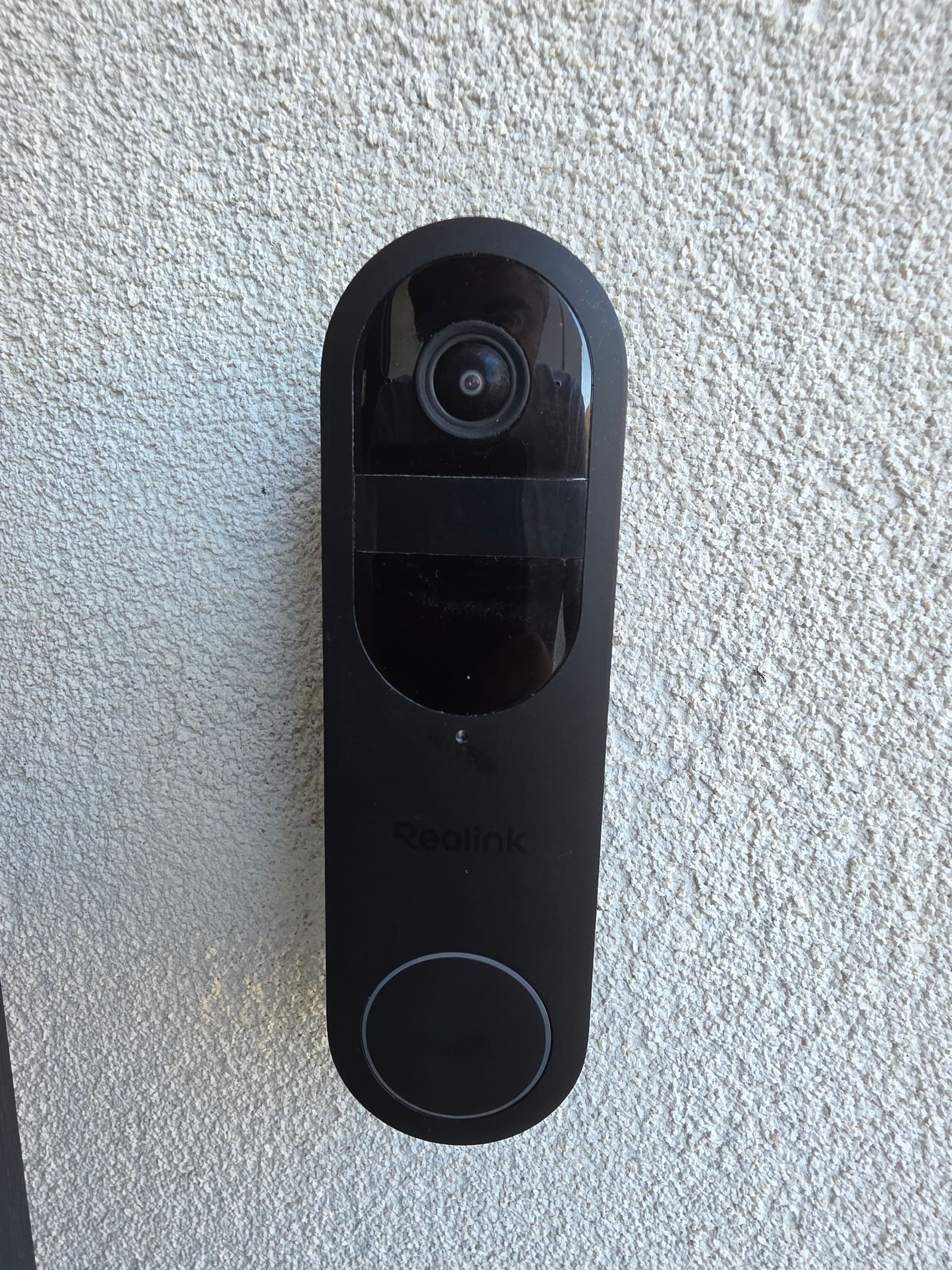 Black Reolink Battery Video Doorbell mounted on the same pebbledash wall